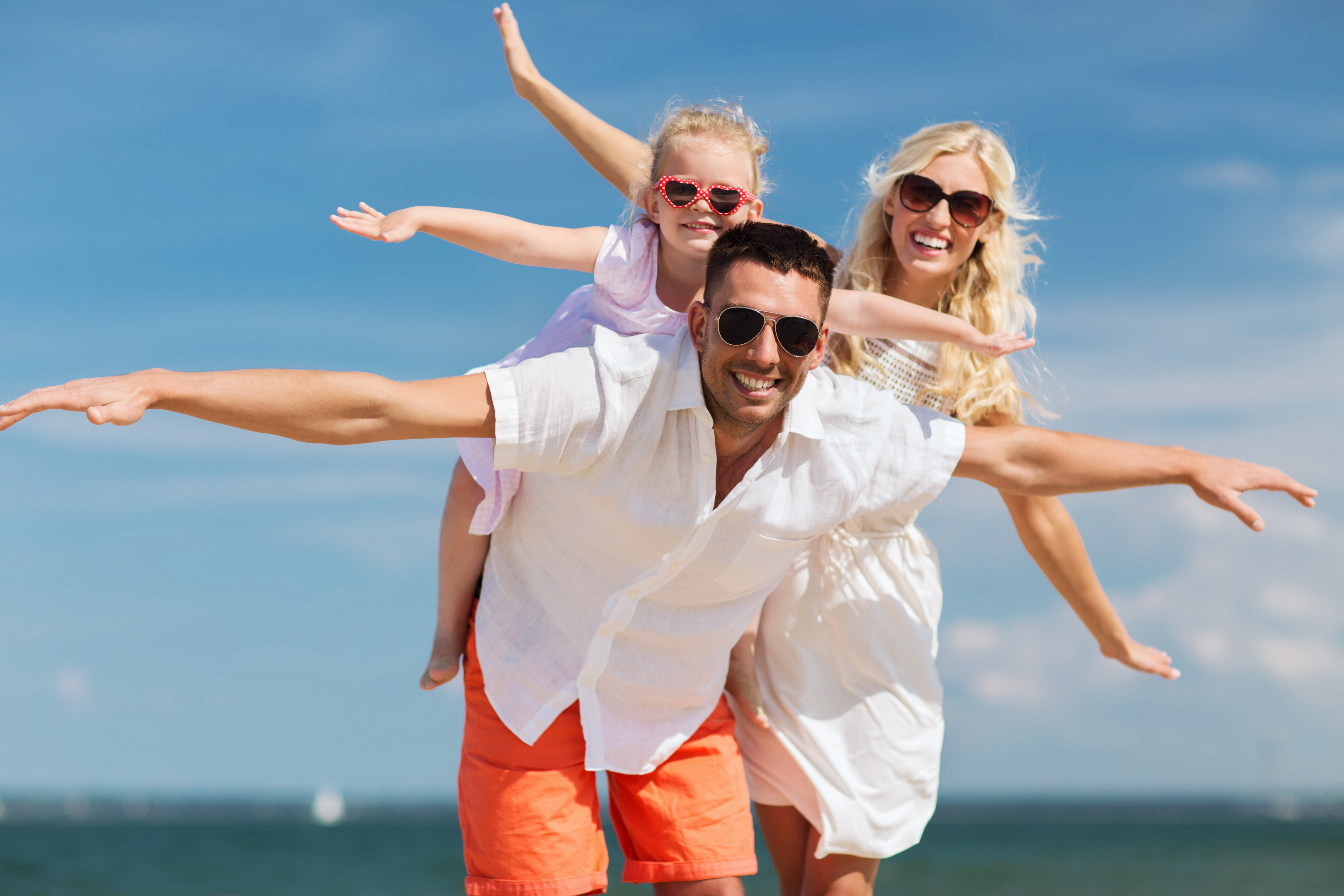 Wakacje bez zmartwień: Odkryj bezpieczne i pełne relaksu lato w ośrodkach Natura Tour! NaturaTour family vacation adoption people concept happy man woman little girl sunglasses having fun summer beach